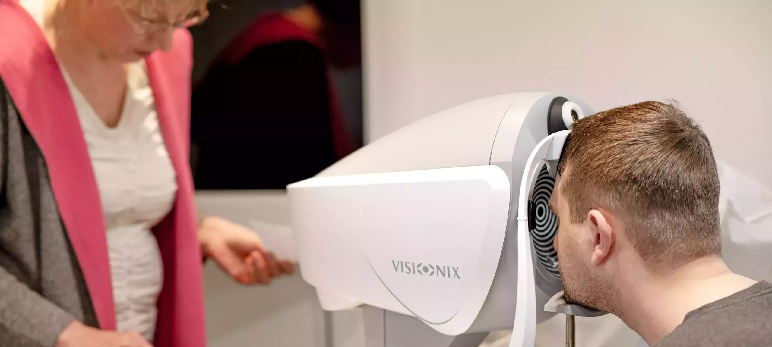 Wellenfrontanalyse Kunde schaut in Wellenfront Gerät, das von Optikerin bedient wird